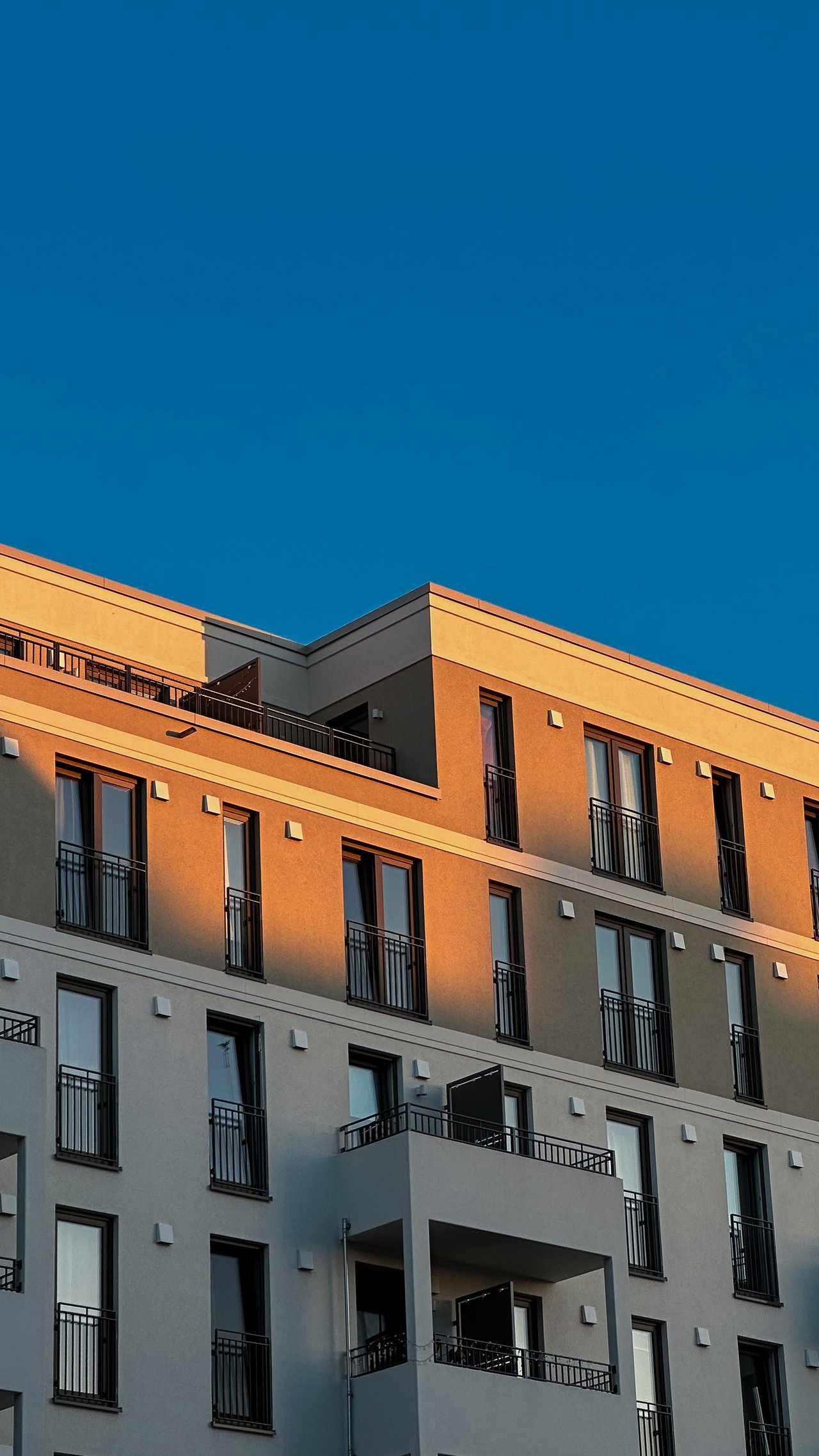 Moderne Mehrfamilien-Wohnhausfassade mit Balkonen im Abendlicht